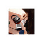 Black Polaroid I-2 instant camera on a wooden table with a person holding a developed film print.