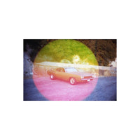 Vintage car parked on asphalt with a large, circular pink and yellow light leak effect from Psychedelic Blues 35mm film.