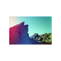 Rocky landscape captured on 35mm film with vibrant red light leaks and teal color shifts across the sky.