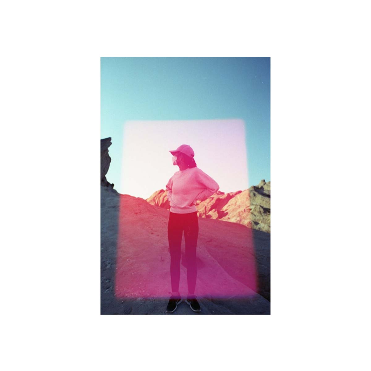 Person standing in a desert landscape captured on 35mm film with a prominent pink rectangular light leak effect.