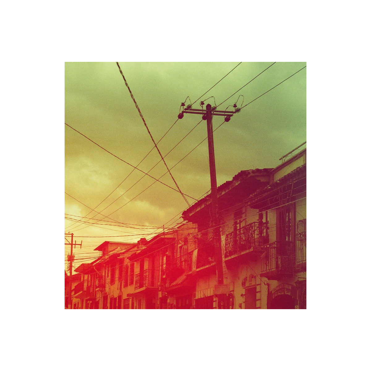 Street scene with utility poles and buildings featuring a vibrant red, yellow, and green color wash effect.