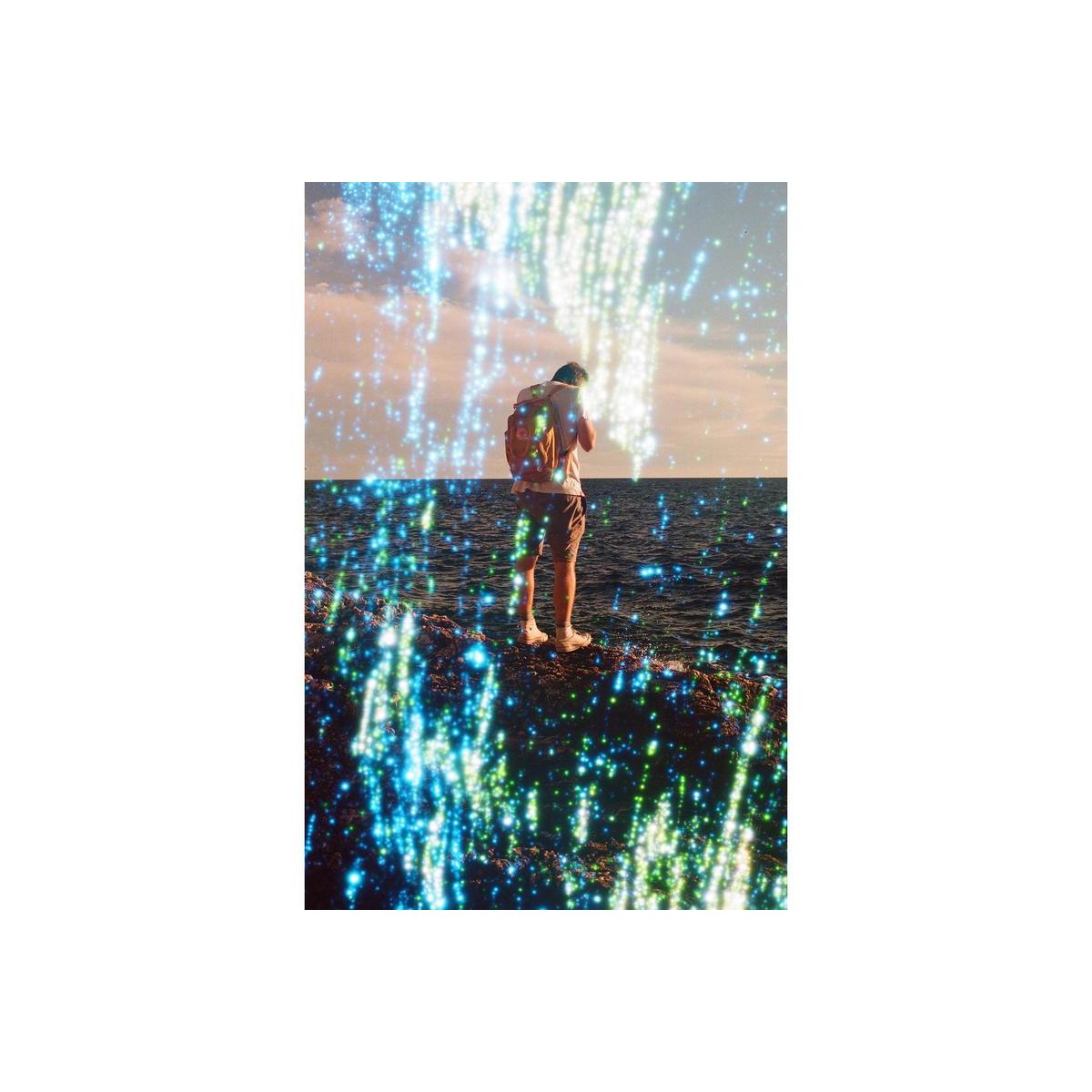 Person standing by the sea at sunset, overlaid with Revolog Nebula 35mm film's signature blue and green stardust effect.
