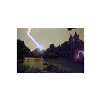 REVOLOG Tesla 1 35mm film shot of a lake with blue lightning bolt effects over a city skyline and trees.