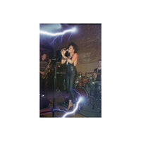 Live band performance captured on 35mm film with a blue lightning bolt effect overlaying the dark stage scene.