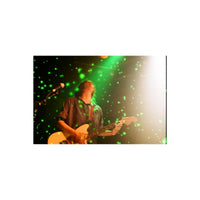 Musician playing guitar on stage with Revolog Volvox 35mm film's signature glowing green dot effect.