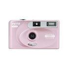 Light pink Reto Project PANO 35mm film camera with a 22mm wide-angle lens, built-in flash, and compact rectangular body.