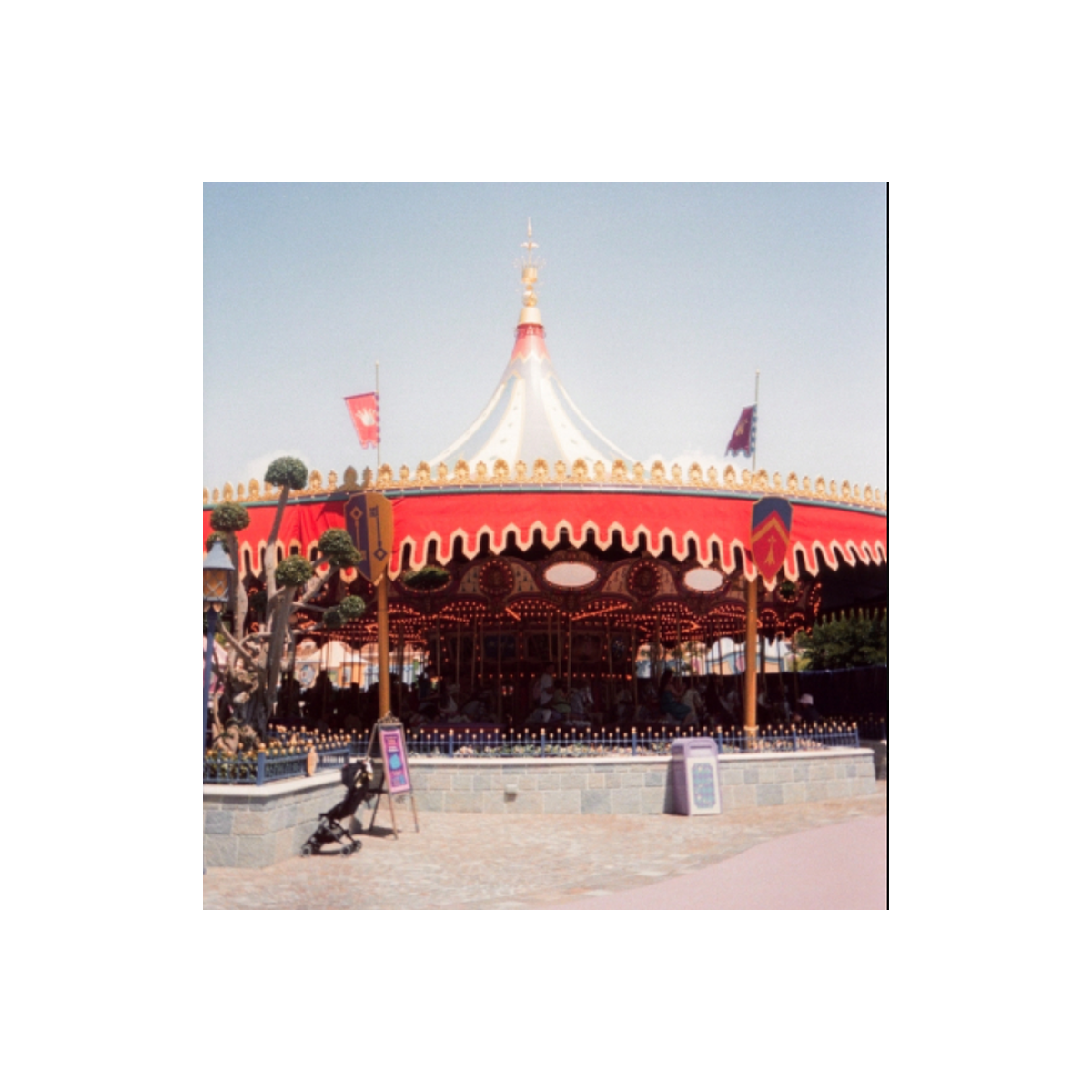 Carousel at a theme park captured on RetoColor Maple 100 film with a distinct cyan-blue cast and vibrant red accents.