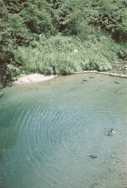 Person swimming in a clear lake surrounded by trees