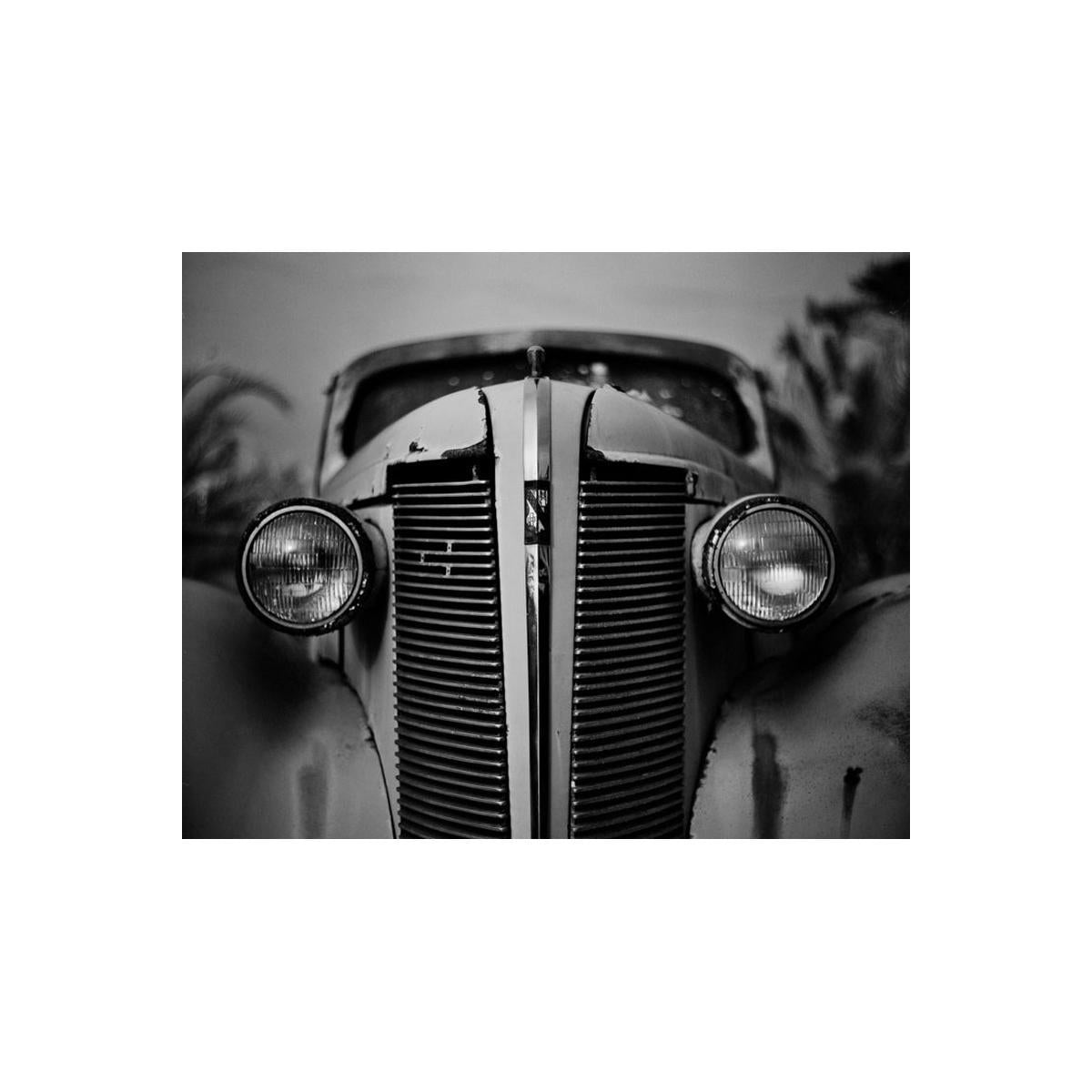 Close-up of a vintage car's front grille and headlights in black and white.