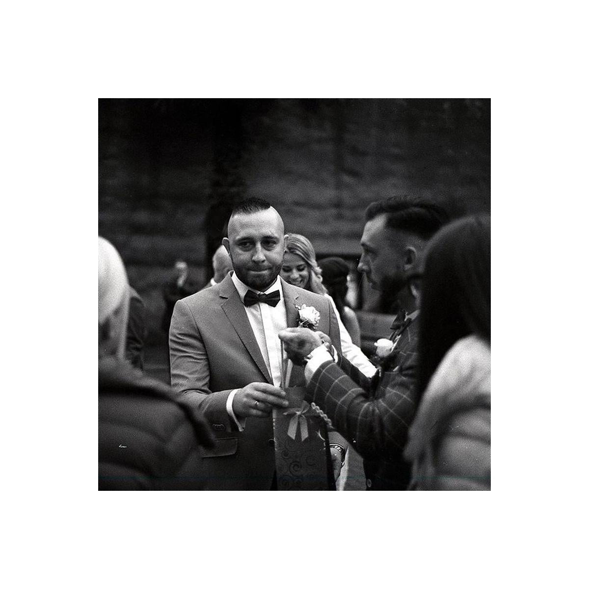 Man in a suit receiving a boutonniere at an event