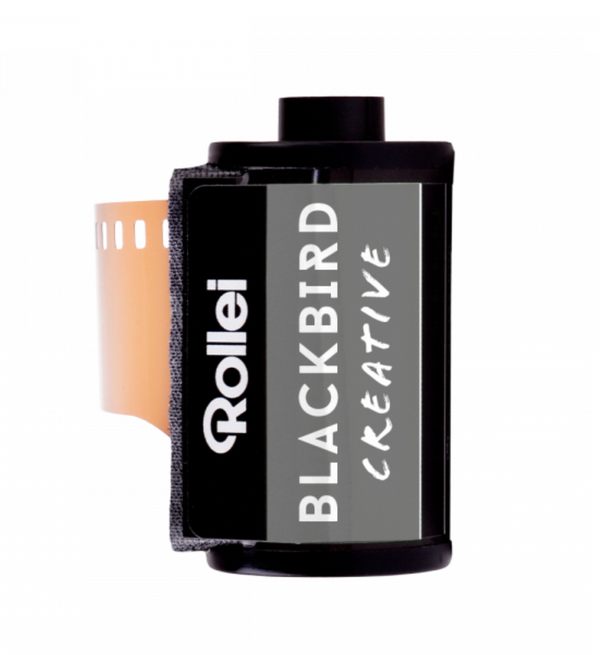 A Rollei Blackbird 100 ISO black and white film canister with the brand and product name visible.
