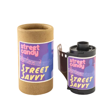 A photograph of a 35mm film canister labeled 'Street Candy Street Savvy' with a musical theme in the background.