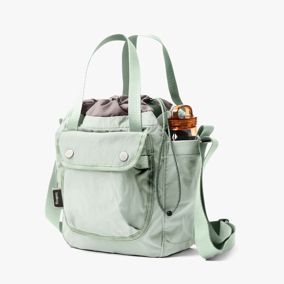 Light green backpack with a bottle inside on a white background