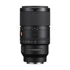 Sony FE 100mm f/2.8 Macro GM lens in black with focus ring, aperture dial, and G Master branding on a white background.