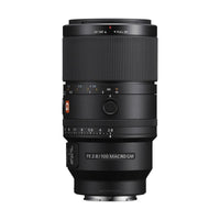 Sony FE 100mm f/2.8 Macro GM lens in black with focus ring, aperture dial, and G Master branding on a white background.