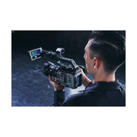 Videographer holding a compact gray Sony FX6 cinema camera with an attached LCD monitor displaying color bars.