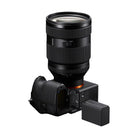 Black Sony NP-SA100 lithium-ion battery placed next to a mirrorless camera with an open battery compartment.