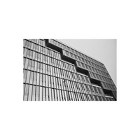 Black and white architectural photograph of a modernist building facade with stepped recesses and vertical window grilles.