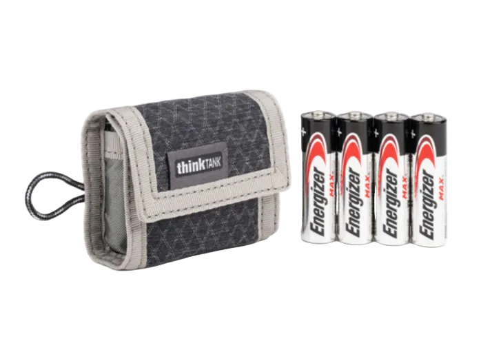 Small gray pouch that says thinktank on it next to 4 batteries on a white background