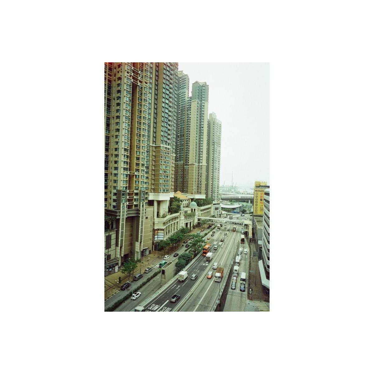 High-angle shot of a city street with tall apartment towers, captured on 35mm color film with soft, vintage-style highlights.