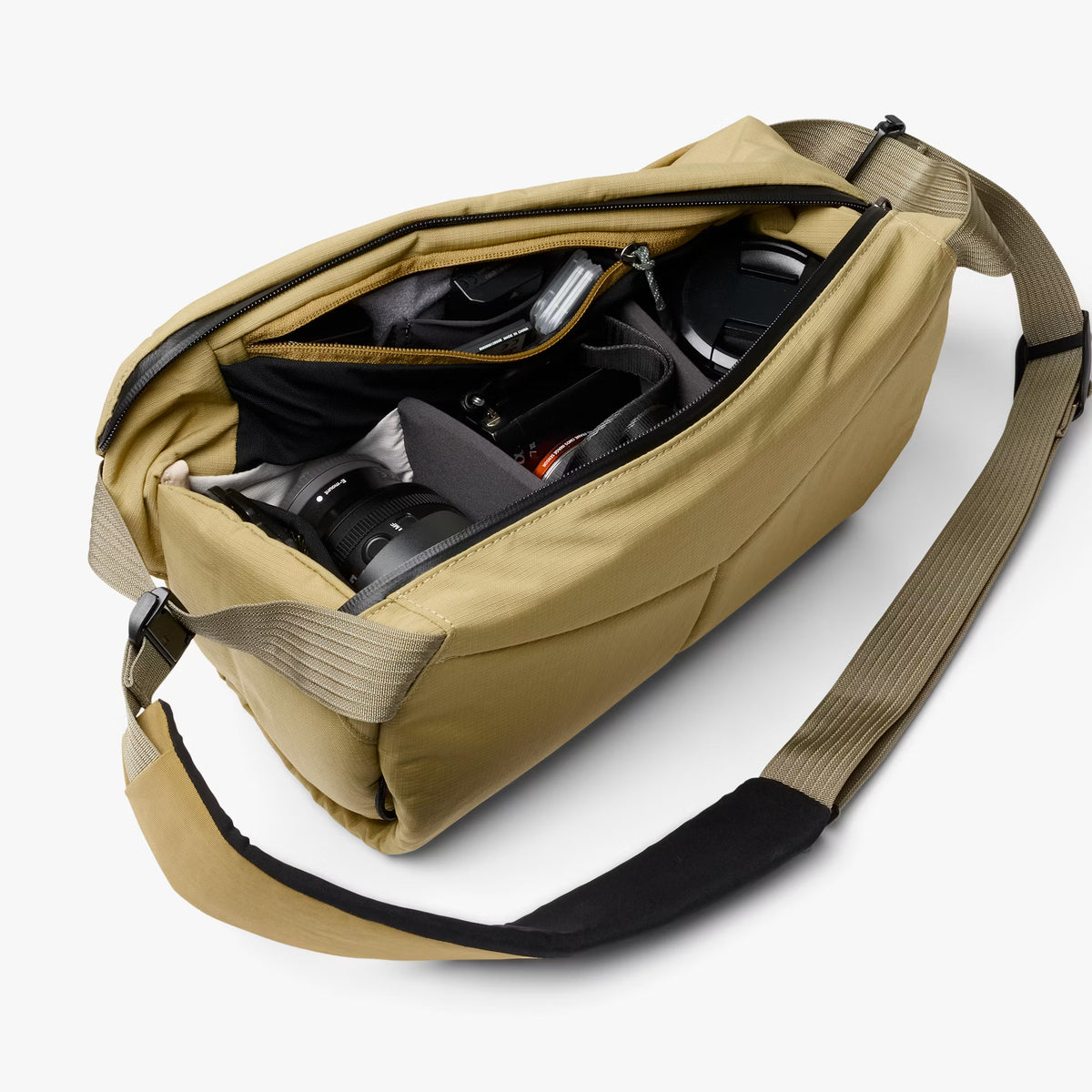 A tan camera bag with an open zipper, showing a camera and lens inside, on a light gray background.