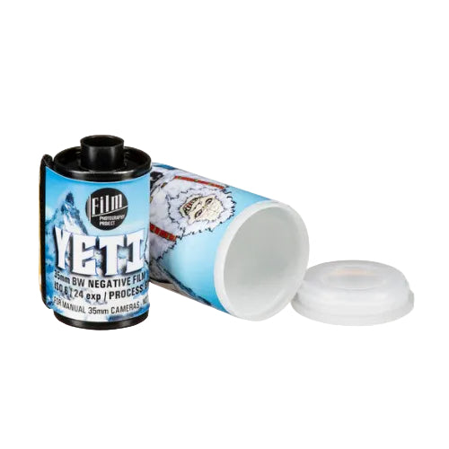 A canister of FILM YETI negative film with its blue and white illustrated label visible, shown alongside a clear plastic lid on a plain white background.