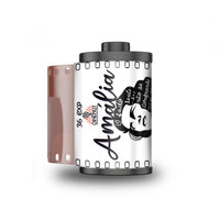 A roll of Amalia 36 Exp film with a black and white retro-style label featuring a woman's profile illustration, shown next to a translucent pink film strip on a white background.