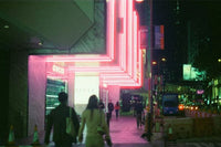 A nighttime street scene featuring a brightly lit Gucci storefront with pink and white neon-like lighting, with pedestrians walking in front of the entrance.