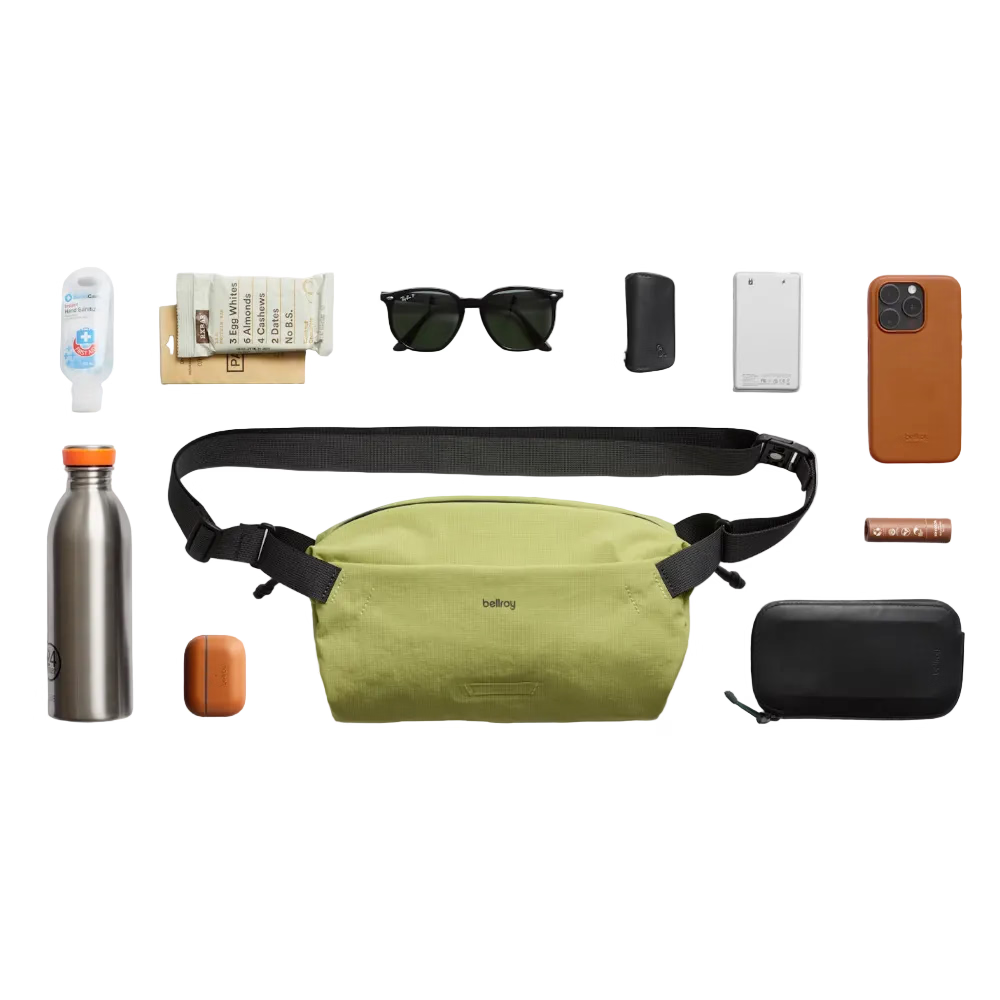 Green waist bag with various items on a white background