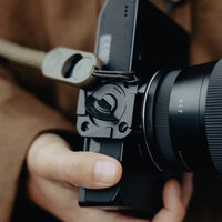 Camera with lens and strap held by a person