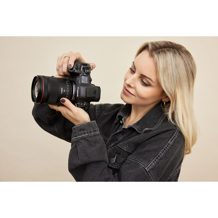 Woman holding a camera against a beige background