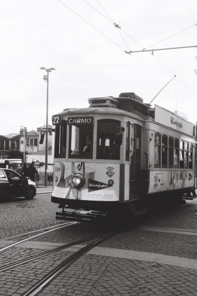 Vintage tram on a street with advertisements and 'Carmo' branding.