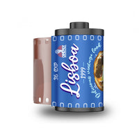 A vintage-style 35mm film roll labeled 'Lisboa 1999' with a blue label, black sprocket edges, and a translucent pink film base visible on the left side, shown on a white background.