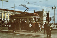Vintage street scene with a tram at a crossroad, surrounded by pedestrians, buildings, overhead wires, and traffic lights, rendered in a warm sepia tone.