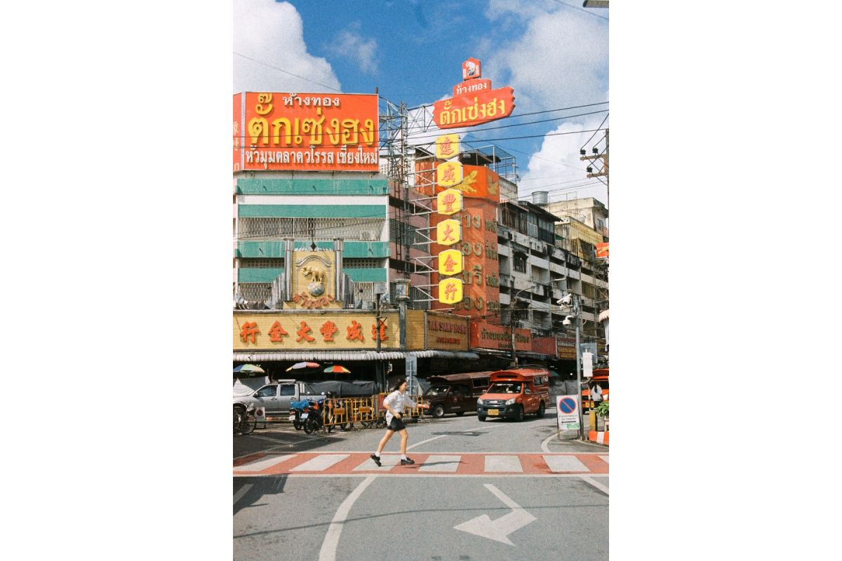 Street scene with colorful building facades and pedestrians crossing a road.
