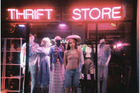 Person standing in front of a thrift store with neon signs and mannequins.