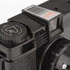 Close-up of a camera lens with a focus indicator light on a black background