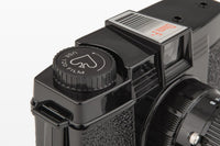 Close-up of a camera lens with a focus indicator light on a black background