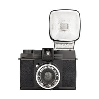 A black Lomography Diana F+ medium format camera with a flash attached to the top, viewed from the front.