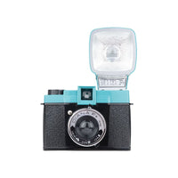 A black and turquoise Lomography Diana F+ camera with a flash attached to the top, viewed from the front.