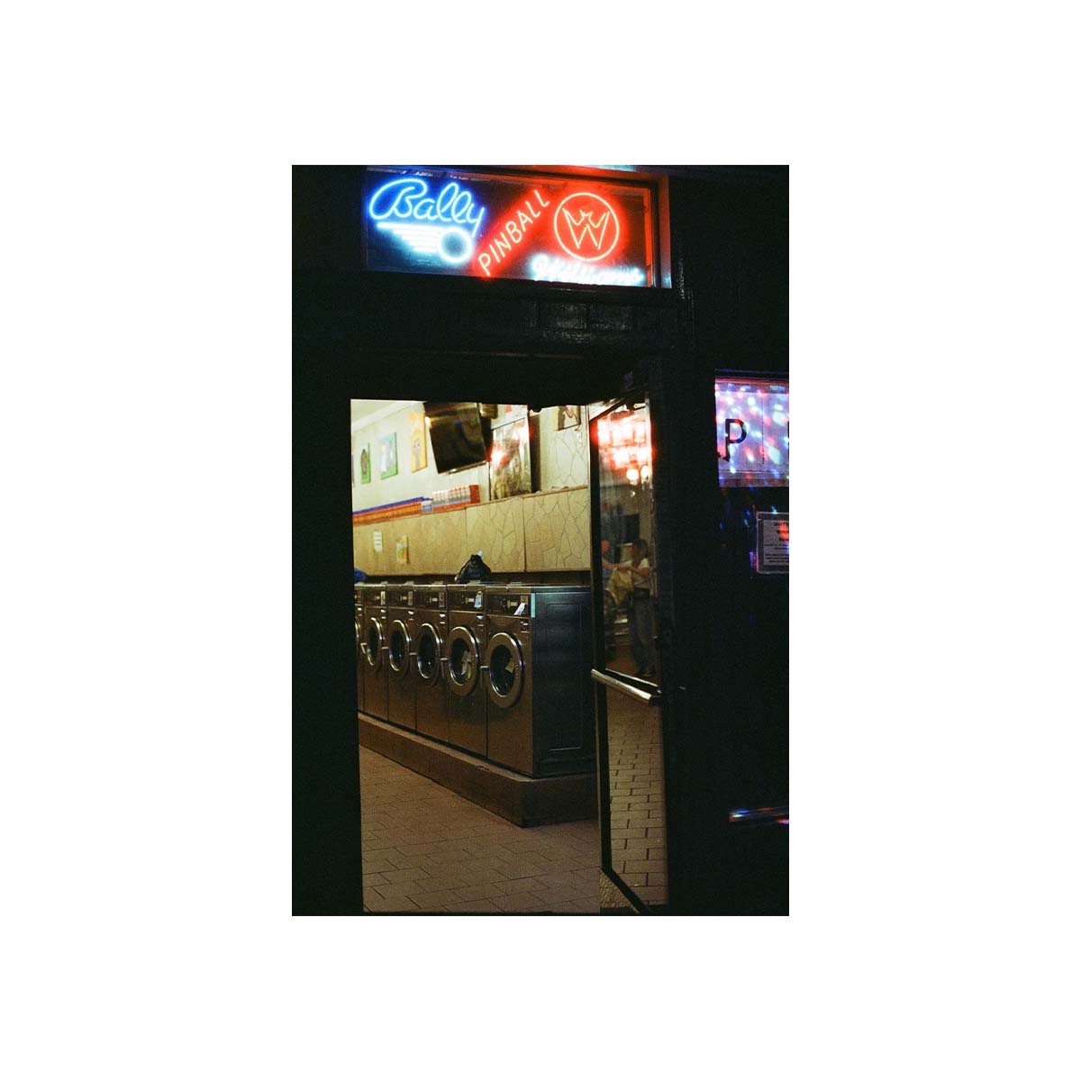 A vertical photographic print of a vintage bowling alley interior, viewed through a dark doorway. A red and blue neon sign at the top reads 'Belly Bowling' and 'PHALLRAMA'.