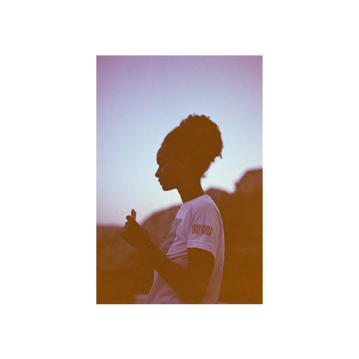 A vertical art print featuring a side-profile silhouette of a person in a white t-shirt against a warm, orange-tinted sunset sky, centered on a white background.