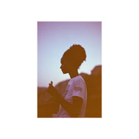 A vertical art print featuring a side-profile silhouette of a person in a white t-shirt against a warm, orange-tinted sunset sky, centered on a white background.