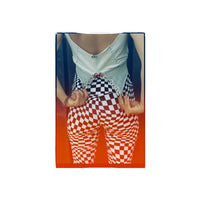 A rectangular product, likely a notebook, journal, or art print, featuring a photographic design of a person from behind wearing a white top and red-and-white checkered pants, set against an orange gradient background.