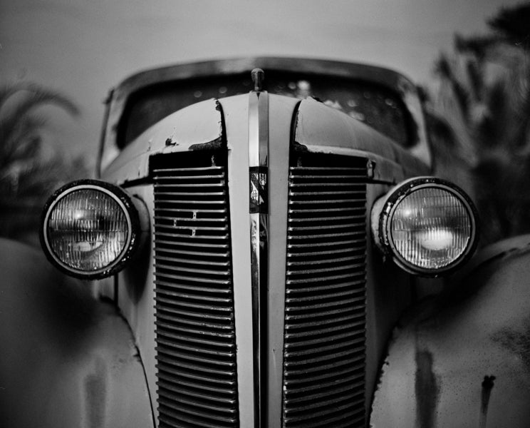 Close-up of a vintage car's front grille and headlights in black and white.