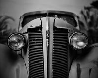 Close-up of a vintage car's front grille and headlights in black and white.