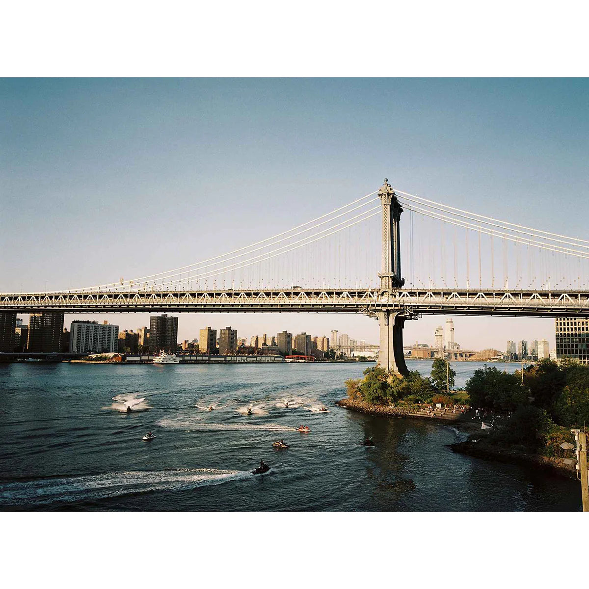 Manhattan Bridge over the East River with boats and city skyline in the background