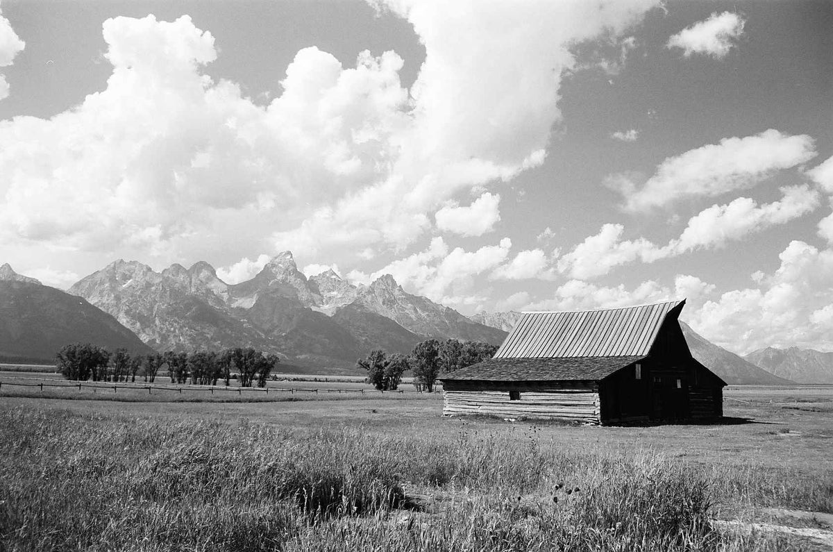 Barn in a field with mountains and clouds in the background