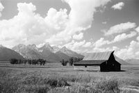 Barn in a field with mountains and clouds in the background
