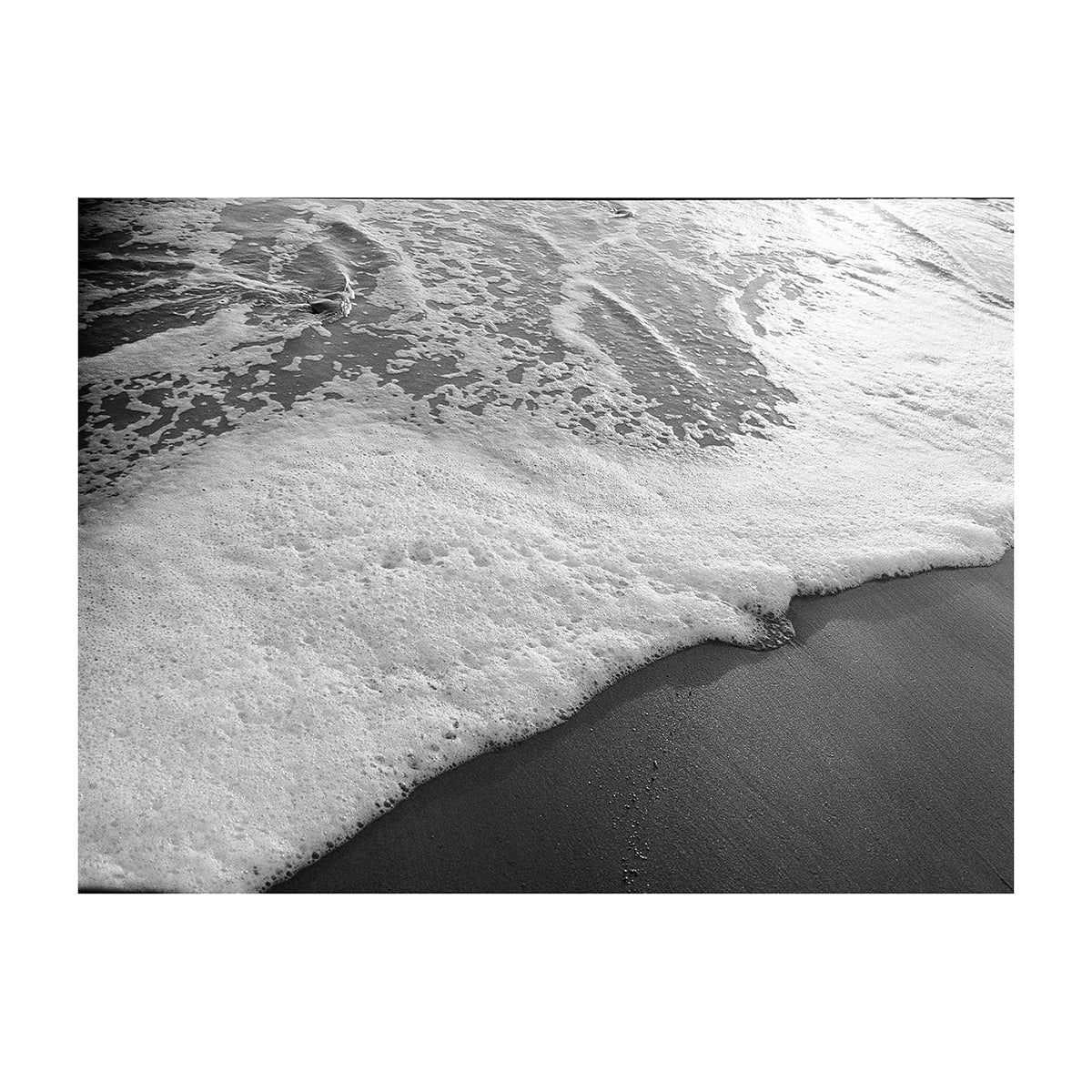 Black and white photo of ocean waves crashing onto a beach